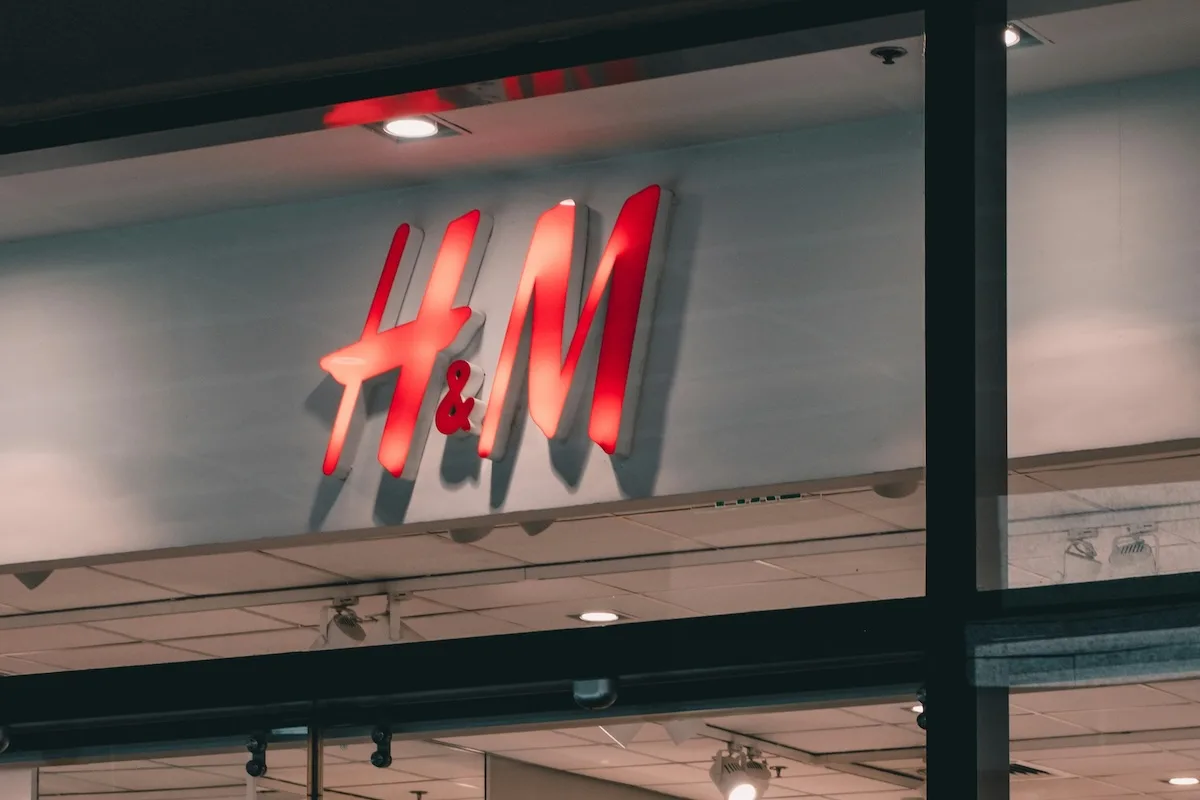 H&M letnia wyprzedaż 2026 ruszyła. Kiedy stacjonarnie i online? Na zdjęciu duże logo H&M nad wejściem do sklepu.