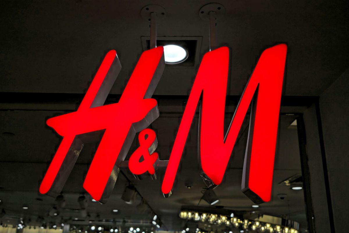 H&M zamyka sklepy. Zbliżenie na podświetlane, czerwone logo H&M znajdujące się przy wejściu do sklepu.