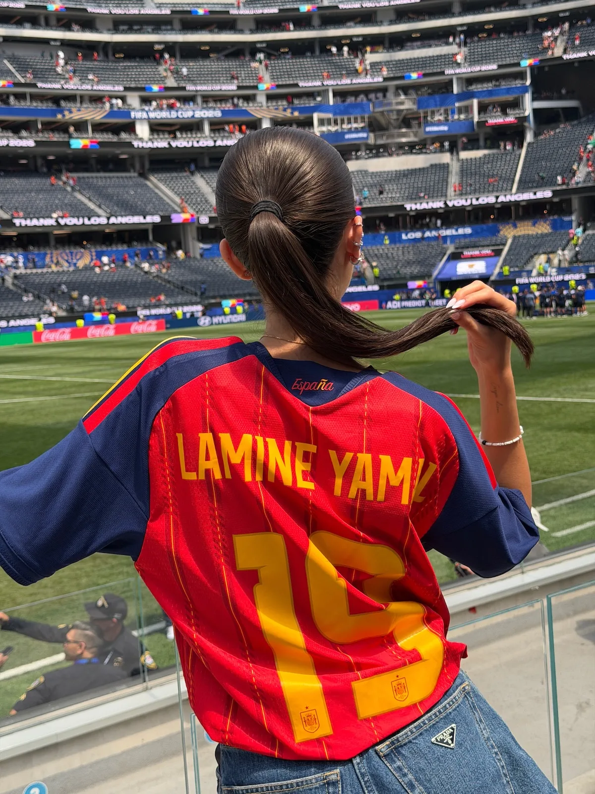 Inés García Santos prezentuje na stadionie koszulkę reprezentacji Hiszpanii z nazwiskiem Lamine’a Yamala na plecach. Zdjęcie wykonano na tle murawy i trybun.