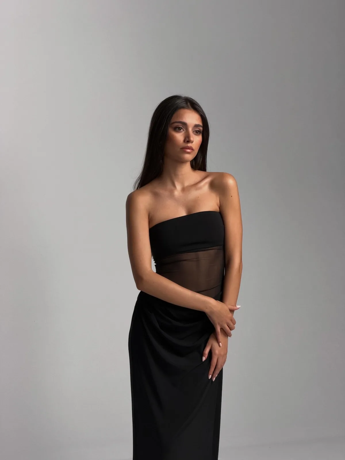 Inés García Santos, dziewczyna Lamine’a Yamala, pozuje w studiu fotograficznym w eleganckiej czarnej sukni bez ramiączek z transparentnym panelem w talii.