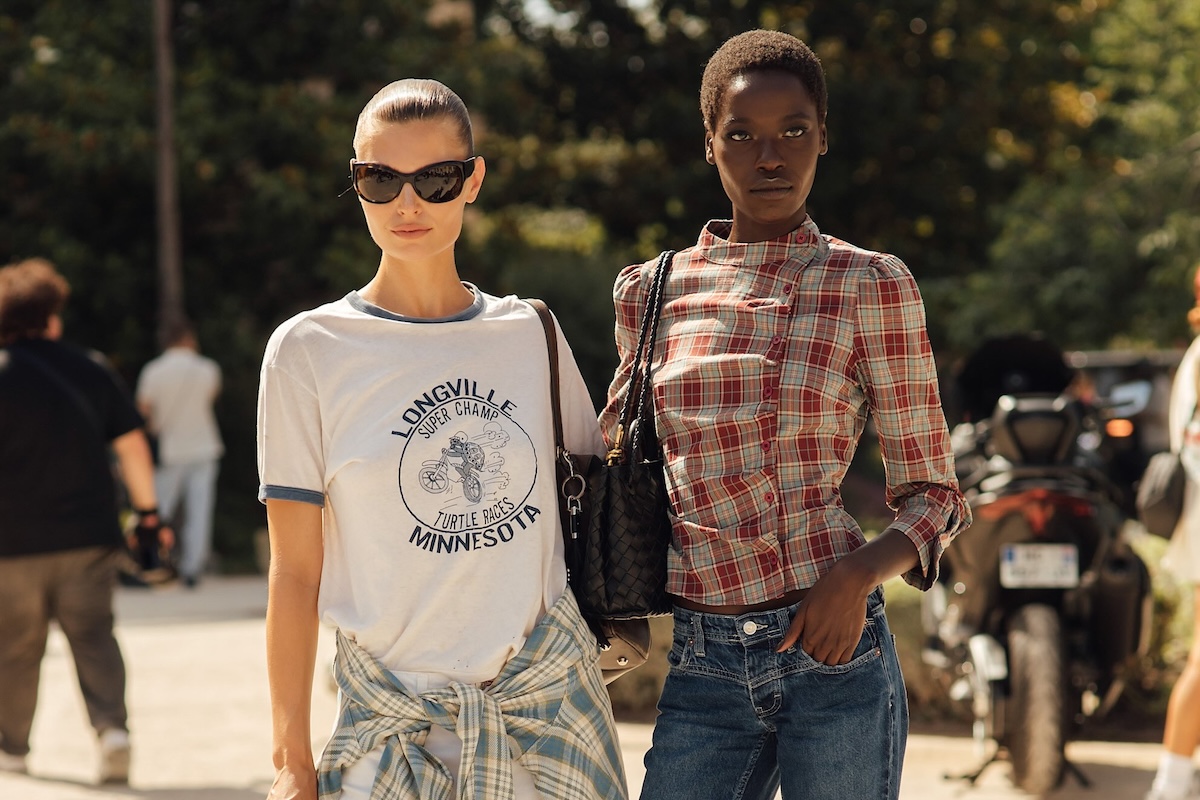 Papryka - Znana marka odzieżowa upada. Na zdjęciu dwie modelki - jedna z nich ubrania w biały t-shirt z nadrukiem, druga w koszulę w kratę.