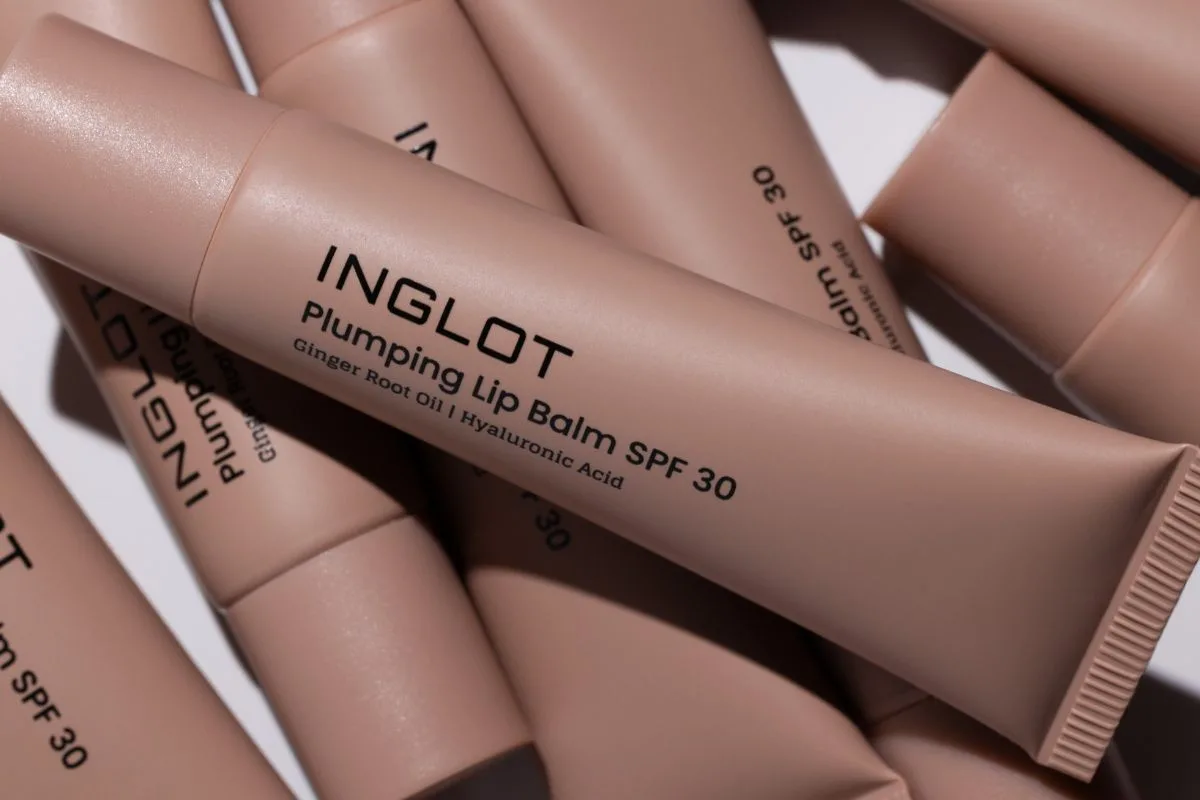 Avallon przejmuje Inglot. Zbliżenie na różowe tubki balsamu Inglot Plumping Lip Balm SPF 30. Na centralnym opakowaniu widoczne jest logo marki oraz informacja o zawartości oleju z imbiru i kwasu hialuronowego.