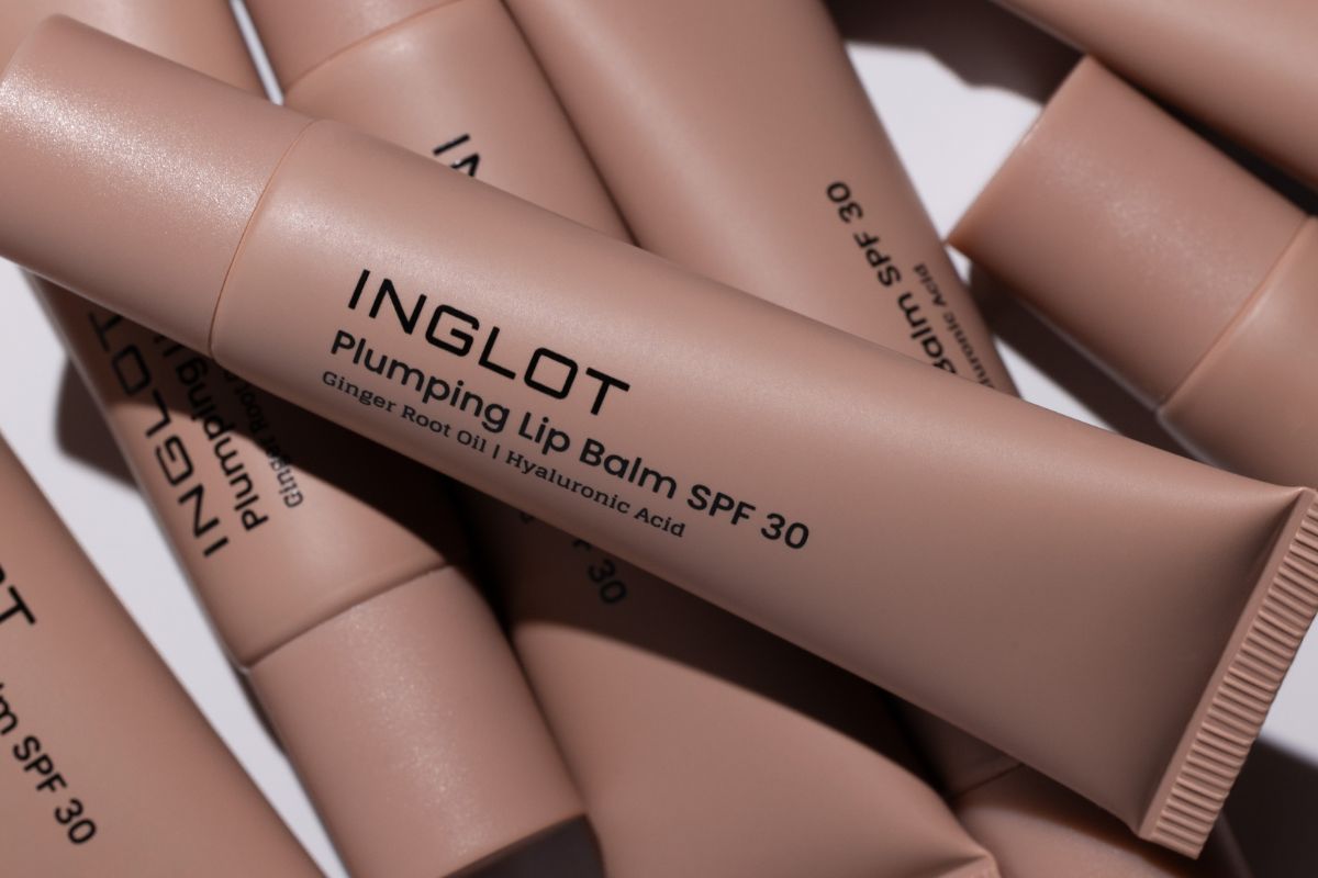 Avallon przejmuje Inglot. Zbliżenie na różowe tubki balsamu Inglot Plumping Lip Balm SPF 30. Na centralnym opakowaniu widoczne jest logo marki oraz informacja o zawartości oleju z imbiru i kwasu hialuronowego.