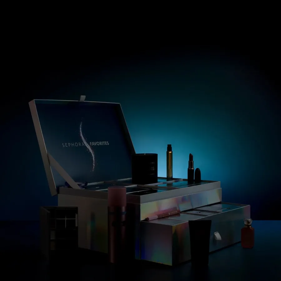 Otwarty kalendarz adwentowy Sephora Favorites 2026 z wysuniętymi szufladkami i kosmetykami ustawionymi wokół pudełka. Ciemna, niebieska aranżacja pokazuje pierwsze produkty z materiałów zapowiadających tegoroczną edycję kalendarza.