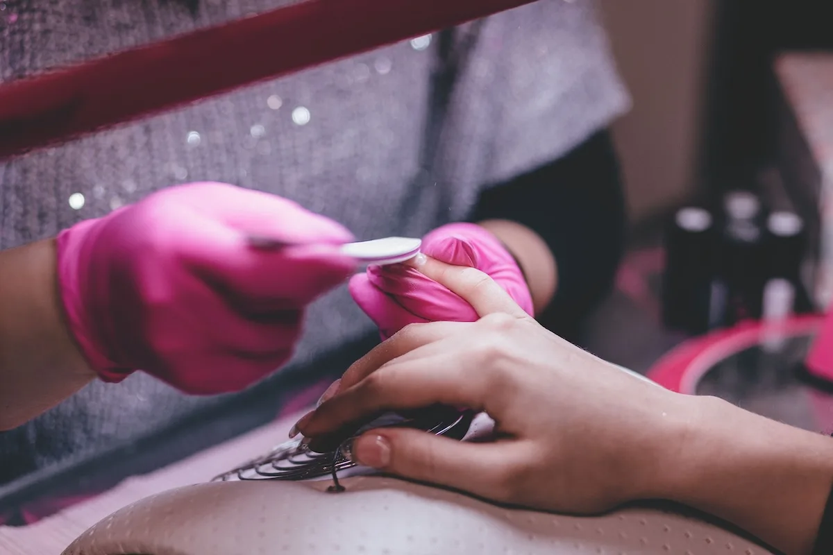 Nowe zasady sterylizacji i higieny. GIS zmienia standardy dla branży beauty. Na zdjęciu zbliżenie na dłonie kosmetyczki robiącej manicure.