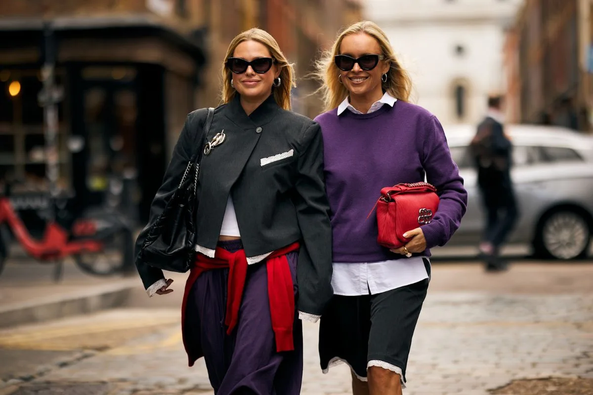 Globalny rynek odzieżowy 2034. Dwie kobiety w casualowych stylizacjach z marynarką i swetrem podczas tygodnia mody.