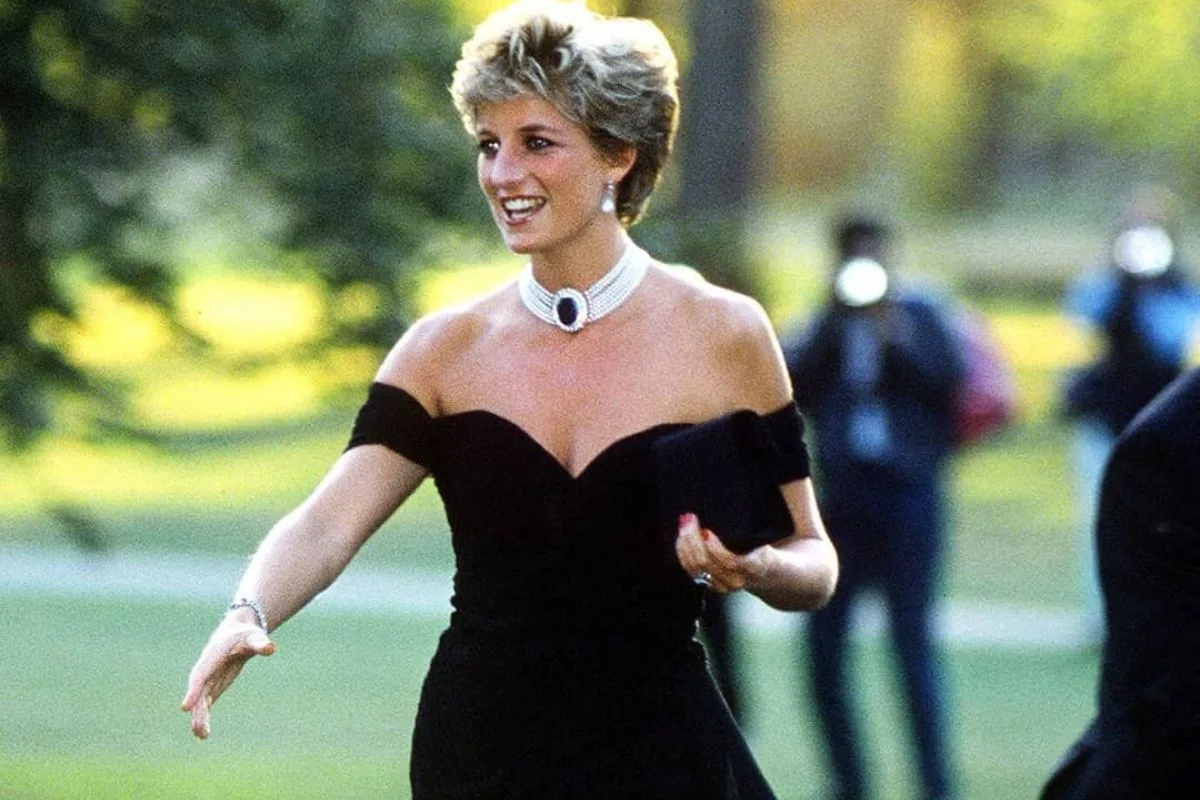 Aukcja Revenge Dress Diany. Księżna Diana w czarnej „revenge dress” podczas przyjęcia w Serpentine Gallery w 1994 roku. Kreację uzupełnia perłowy naszyjnik z ciemnym kamieniem oraz czarna kopertówka.