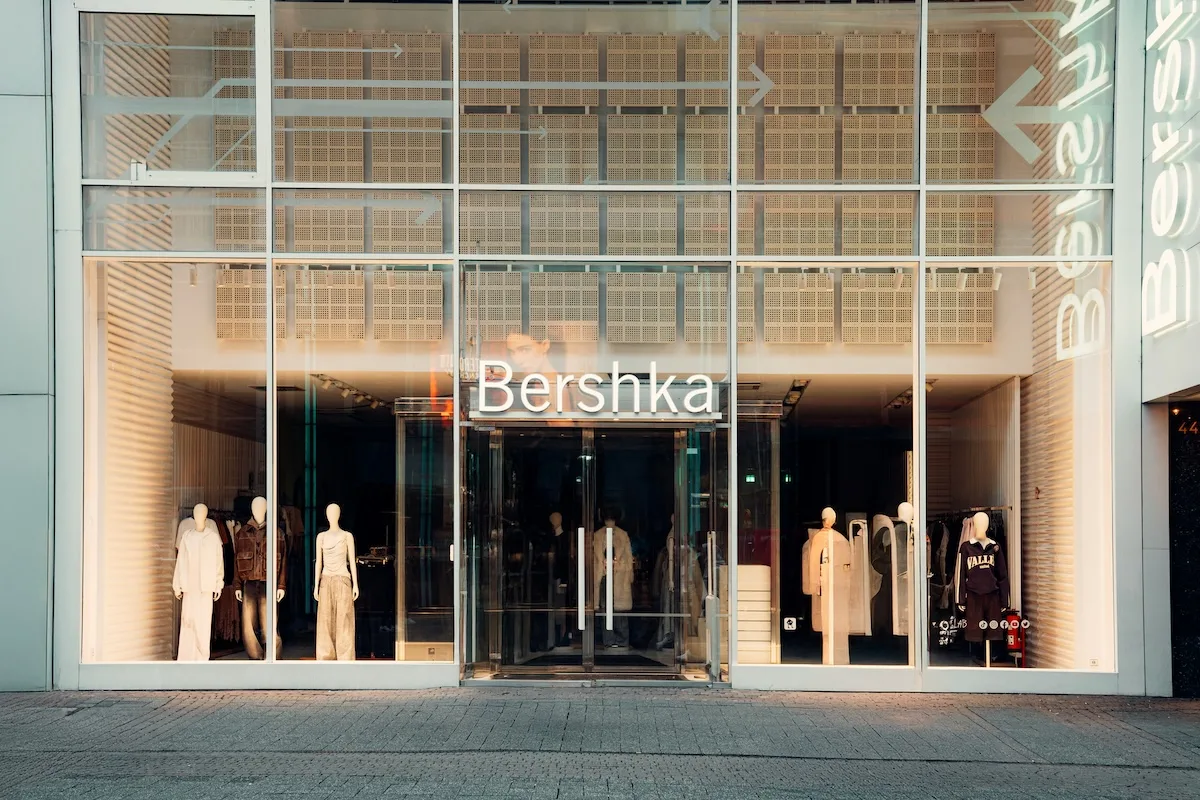 Witryna sklepu Bershka z dużym logo marki, szklanym wejściem i manekinami prezentującymi kolekcję ubrań.