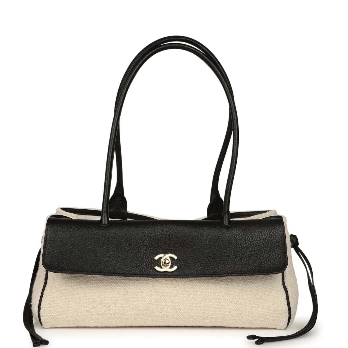 Torebka Chanel Urban Essential z jasnego płótna, z czarną skórzaną klapą, złotym logo CC, długimi uchwytami i bocznymi wiązaniami.
