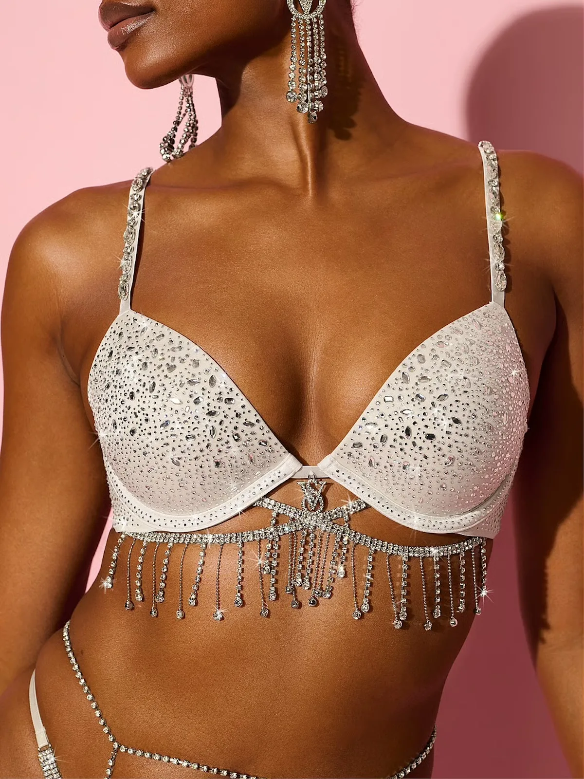 Modelka w białym biustonoszu Very Sexy Shine Fantasy Bra Victoria’s Secret za 398 dolarów, ozdobionym kryształkami, błyszczącymi ramiączkami i zwisającymi frędzlami.