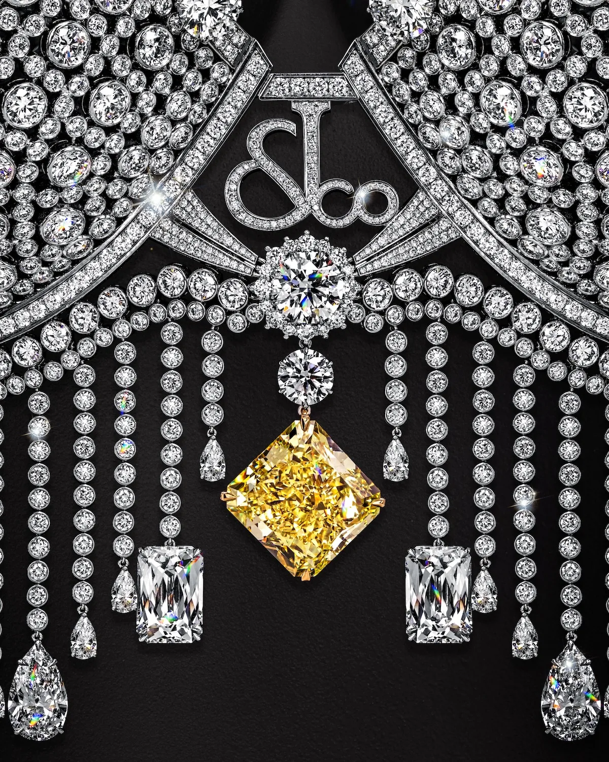 Zbliżenie na centralną część Fantasy Bra Victoria’s Secret – diamentowy monogram jubilera, zwisające łańcuszki i duży żółty diament w ozdobnej oprawie.