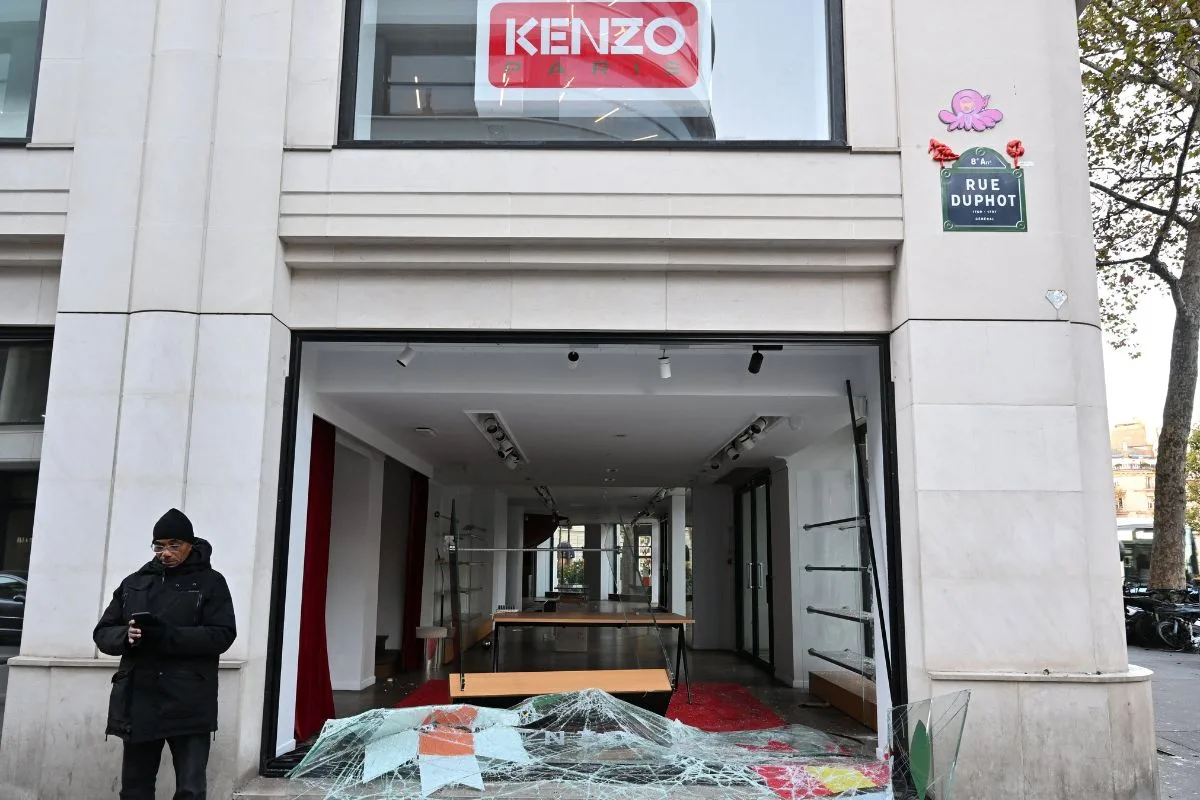 Zniszczony butik Kenzo przy Rue Duphot w Paryżu. Wybita witryna, potłuczone szkło na chodniku i niemal pusty lokal po splądrowaniu sklepu.
